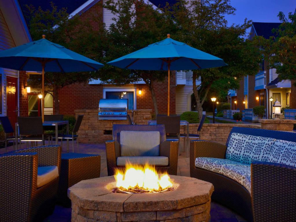 a fire pit in a patio with chairs and umbrellas at Sonesta ES Suites South Brunswick - Princeton in South Brunswick Terrace