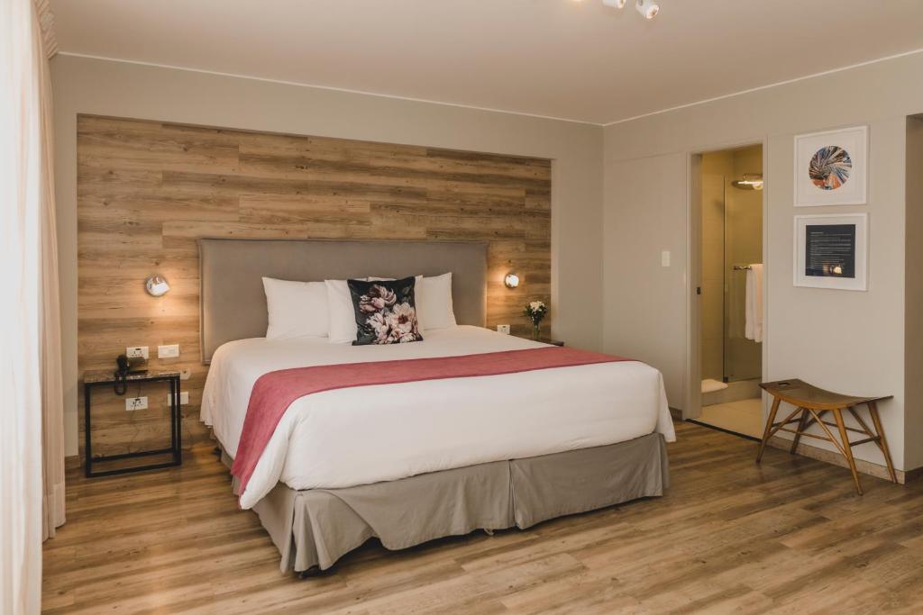 1 dormitorio con 1 cama grande y pared de madera en ARTE HOTEL Lima, en Lima