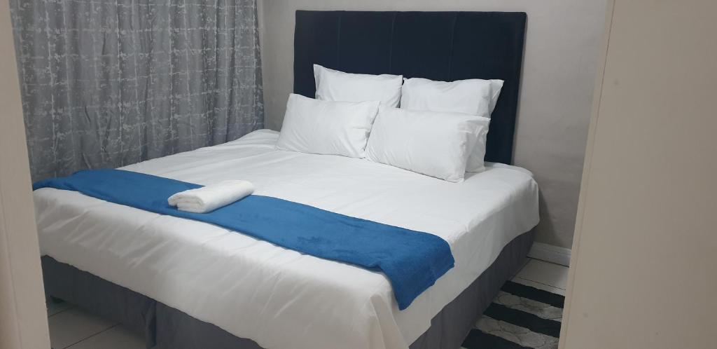 a bed with a blue and white blanket on it at Georgina Self-Catering Flat in George
