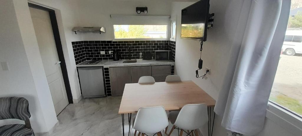 una pequeña cocina con mesa de madera y sillas en VERA Apart, en El Chaltén