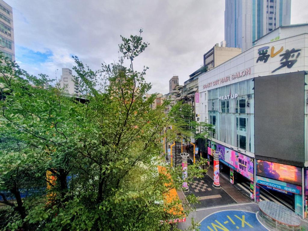 a city street with tall buildings and a tree at Rainbow Hotel in Taipei