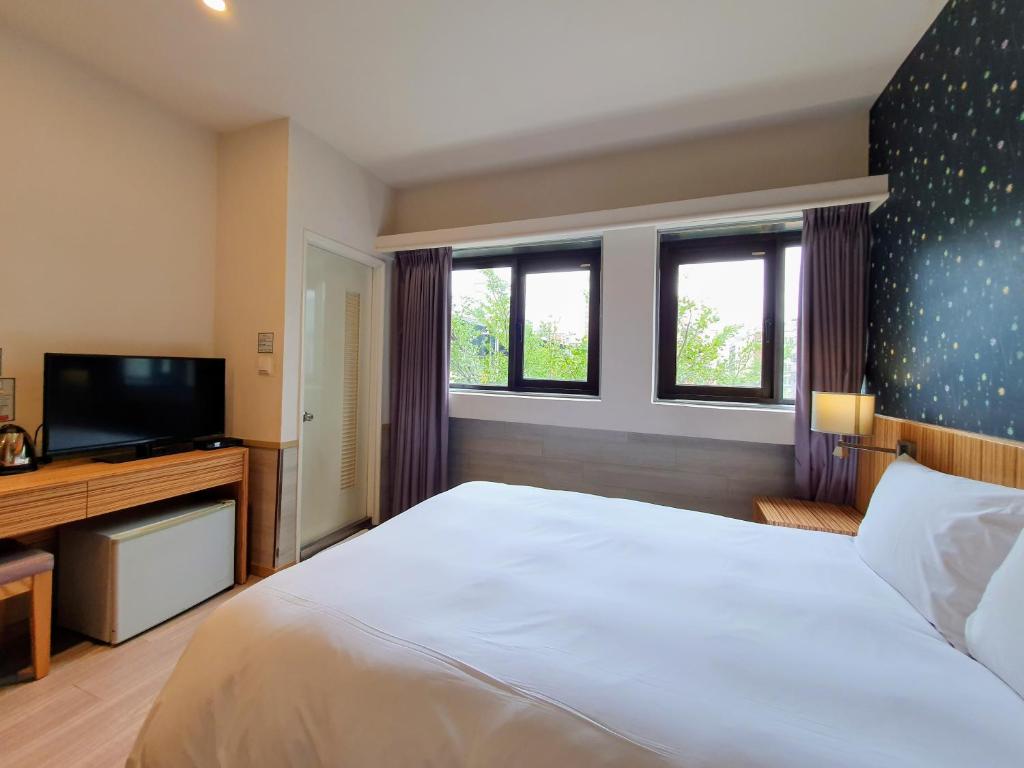 a bedroom with a large bed and a flat screen tv at Rainbow Hotel in Taipei