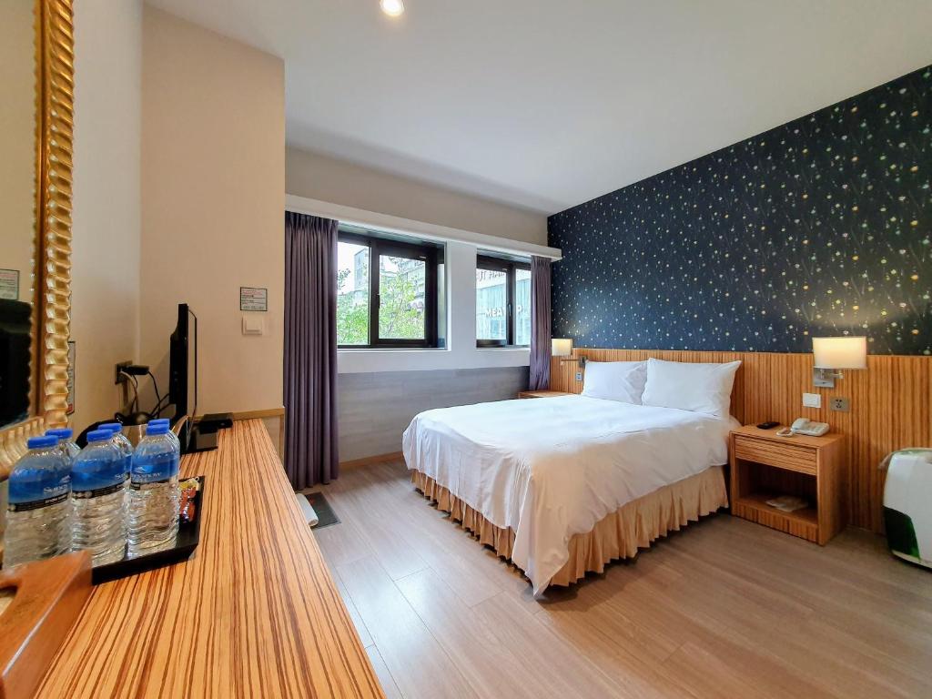 a bedroom with a bed and a wall with bottles of water at Rainbow Hotel in Taipei