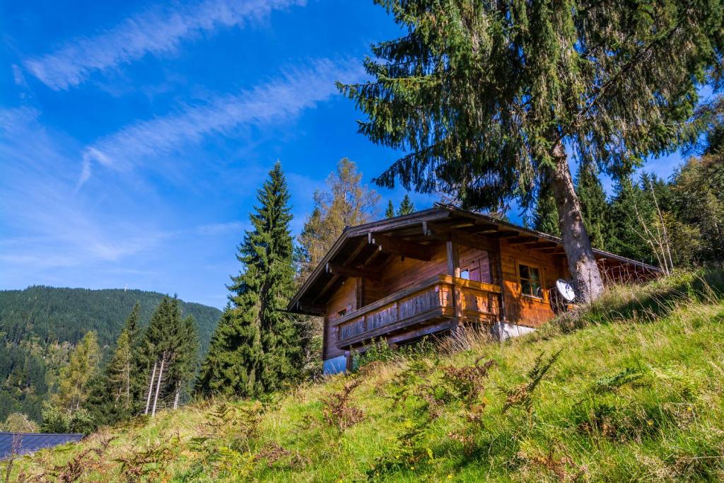 a log cabin on a hill with a tree at Chalets Ebner in Eben im Pongau