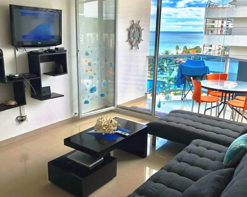 a living room with a couch and a tv and a table at Hermoso departamento frente al mar, Arena Plaza in Tonsupa