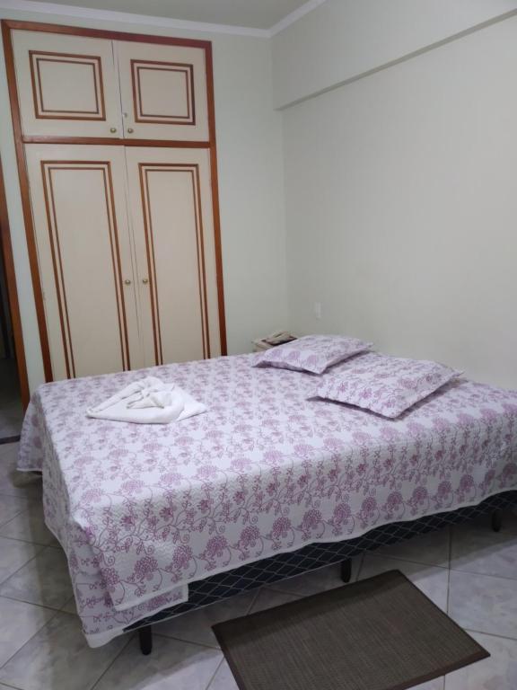 a bedroom with a bed with a purple blanket at Apartamento Hotel Cavalinho Branco in Águas de Lindóia