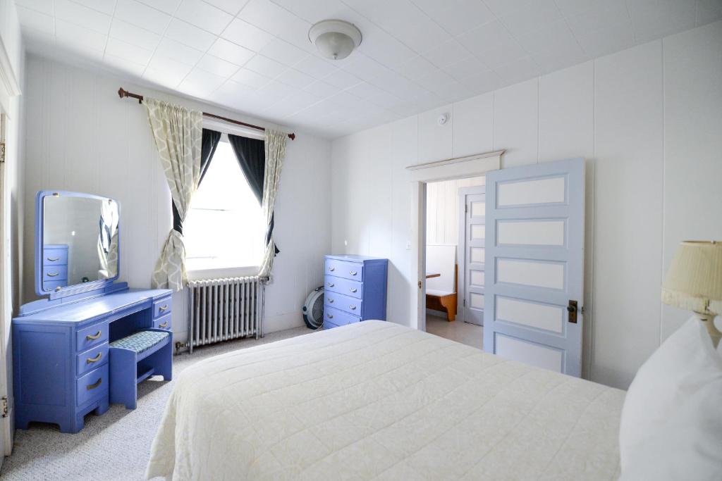 a bedroom with a white bed and a blue dresser at Brown & Hawkins Historical Apartments in Seward