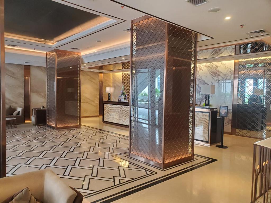 a lobby with a glass elevator in a building at Alexa Meisterstadt pollux habibie in Batam Center