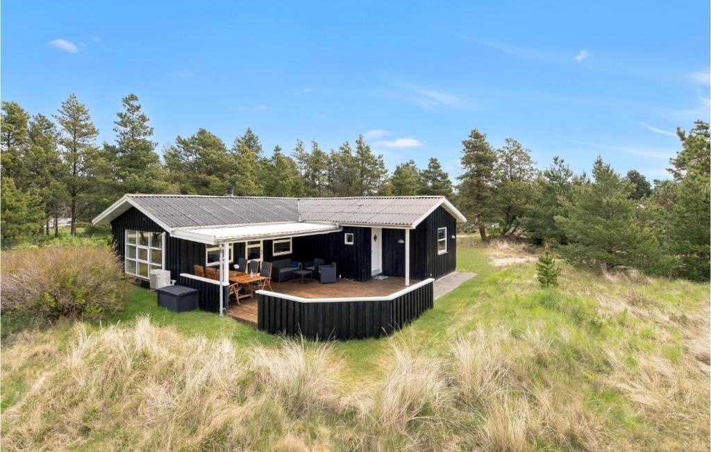 una capanna nera in mezzo a un campo di Cozy Home In Blåvand With Wifi a Blåvand
