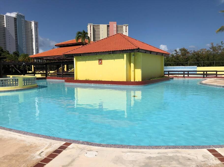 法哈多的住宿－Casa Rosado @ Villa Marina Fajardo Pool Yunque，一座黄色和绿色建筑的大型游泳池