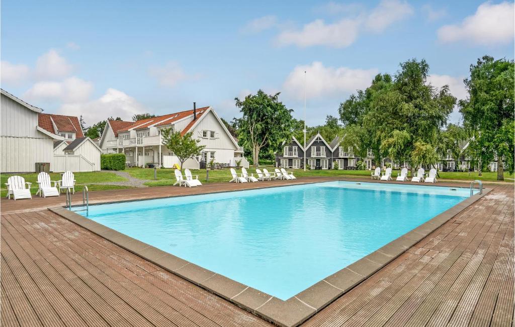 a swimming pool with white chairs and a house at Cozy Apartment In Nykbing Sj With Outdoor Swimming Pool in Rørvig