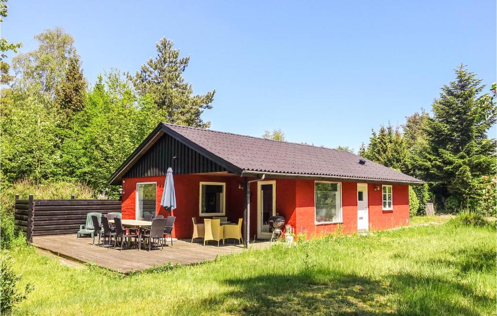 ein rotes Haus mit einer Terrasse und einem Tisch in der Unterkunft 3 Bedroom Lovely Home In Rnne in Rønne