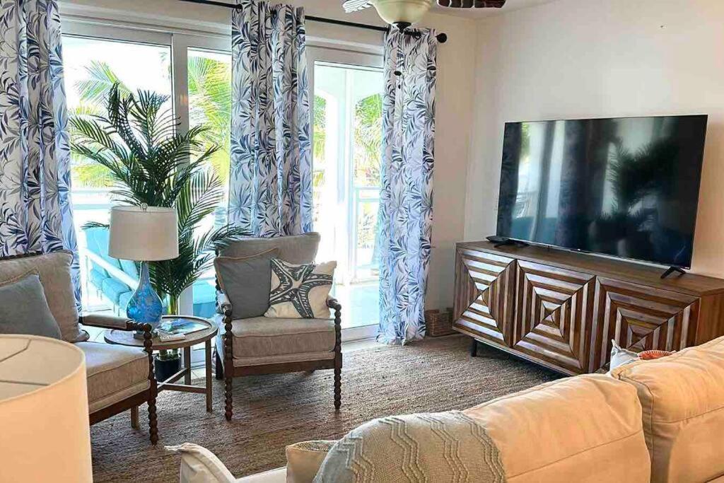 馬霍礁的住宿－Lux Maho Reef 1BR Suite Condo next to The Morgan Resort，客厅配有平面电视和椅子