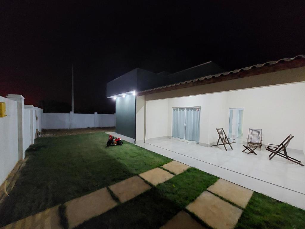 un patio trasero con sillas y césped por la noche en Linda casa na cidade de Chapada dos Guimarães/MT., en Chapada dos Guimarães