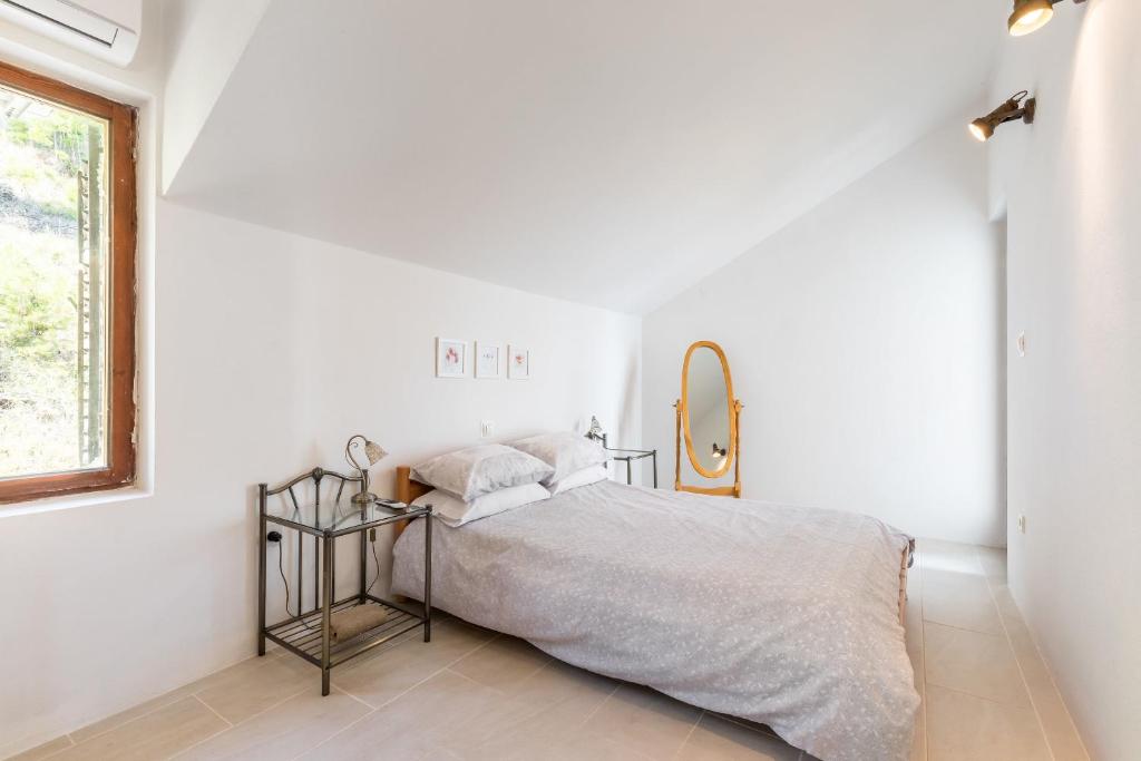 a white bedroom with a bed and a mirror at Apartment Nadia in Lokva Rogoznica