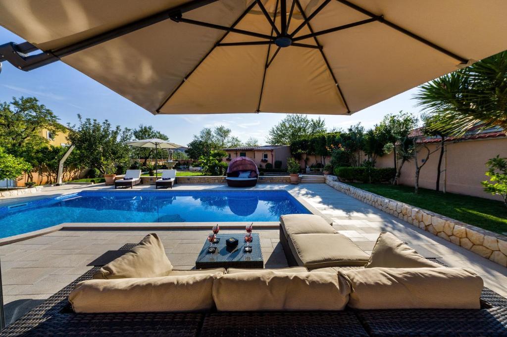 Pool mit Couch und Sonnenschirm daneben in der Unterkunft Villa Beauty Luxury Vodice in Vodice