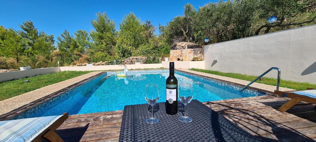 uma garrafa de vinho sentada numa mesa ao lado de uma piscina em Villa Ivana em Dol