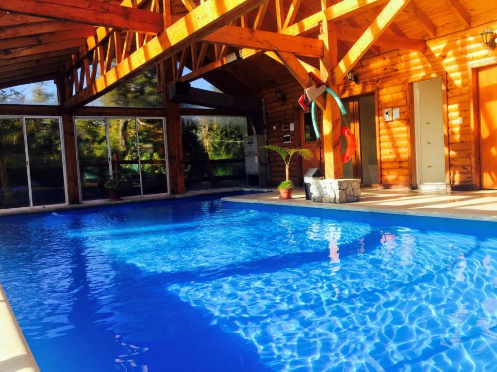a large swimming pool in a house with a wooden ceiling at Encanto del Rio in Villa La Angostura