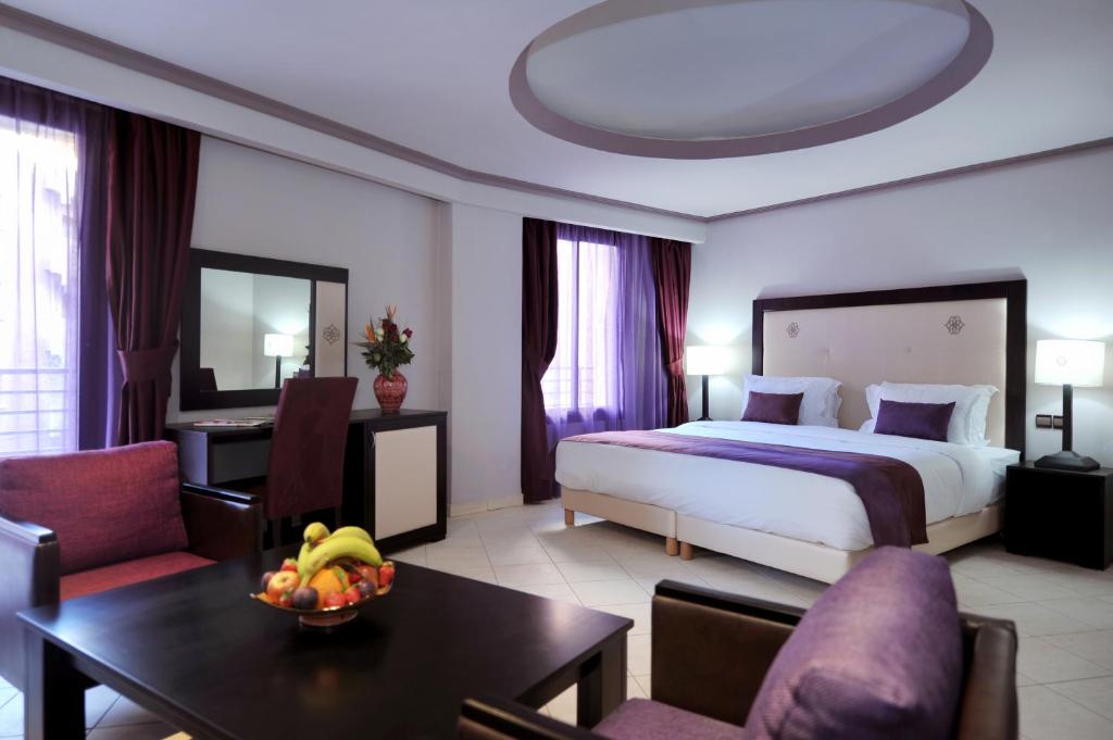 ein Hotelzimmer mit einem Schlafzimmer mit einem Bett und einem Tisch in der Unterkunft Blue Sea Le Printemps in Marrakesch