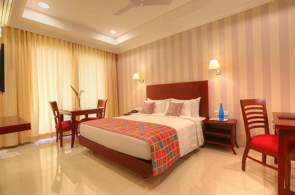 a hotel room with a bed and a table and chairs at Lilac Hotel 3rd Block in Bangalore