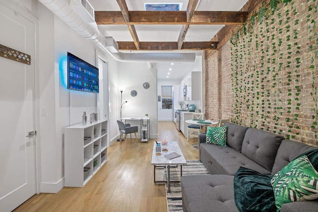 a living room with a couch and a brick wall at Chic Industrial Home In City Center in Hoboken