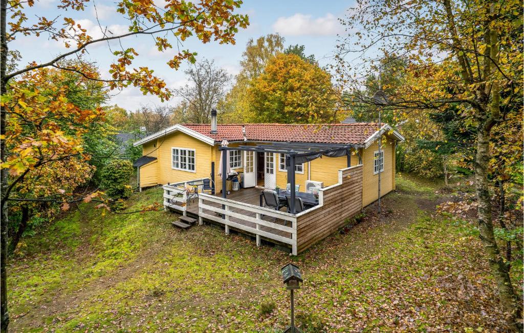 une petite maison jaune avec une terrasse couverte dans les bois dans l'établissement 3 Bedroom Cozy Home In Brkop, à Børkop