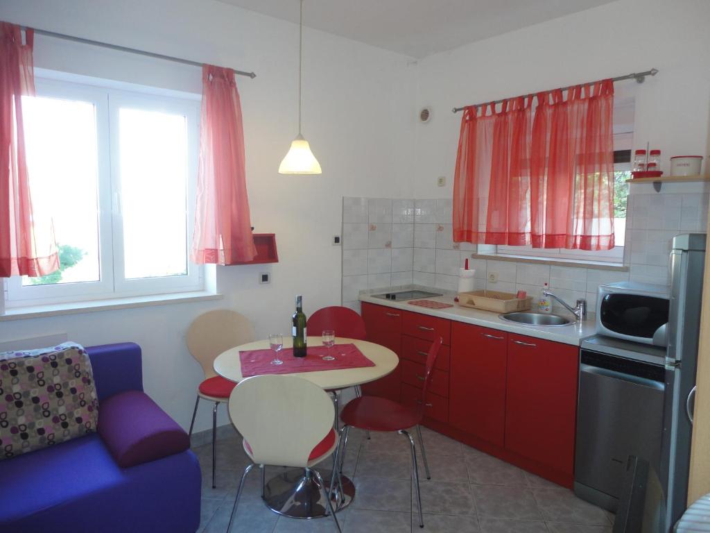 a kitchen with red cabinets and a table and a blue couch at Lozna Apartment in Postira