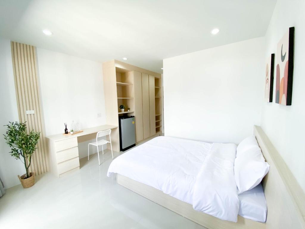 a white bedroom with a bed and a desk at Rest Suvarnabhumi in Samutprakarn