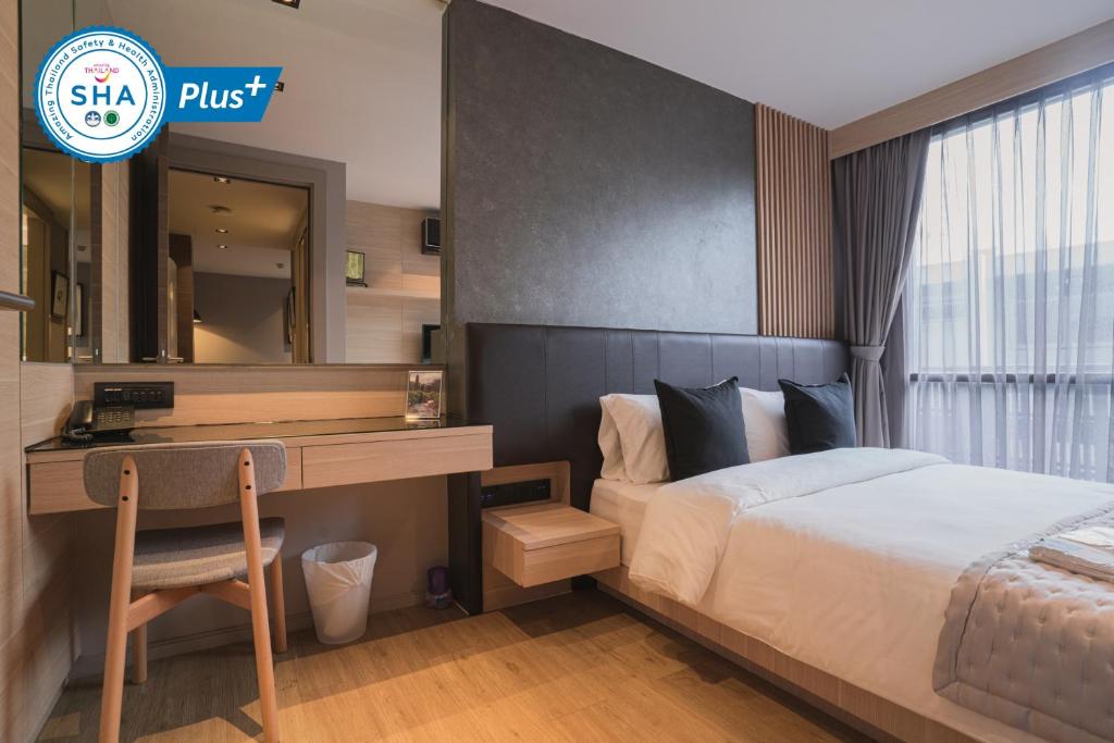 a bedroom with a bed and a desk and a mirror at VOQUE Hotel & Serviced Residence Sukhumvit 51 - SHA Plus in Bangkok