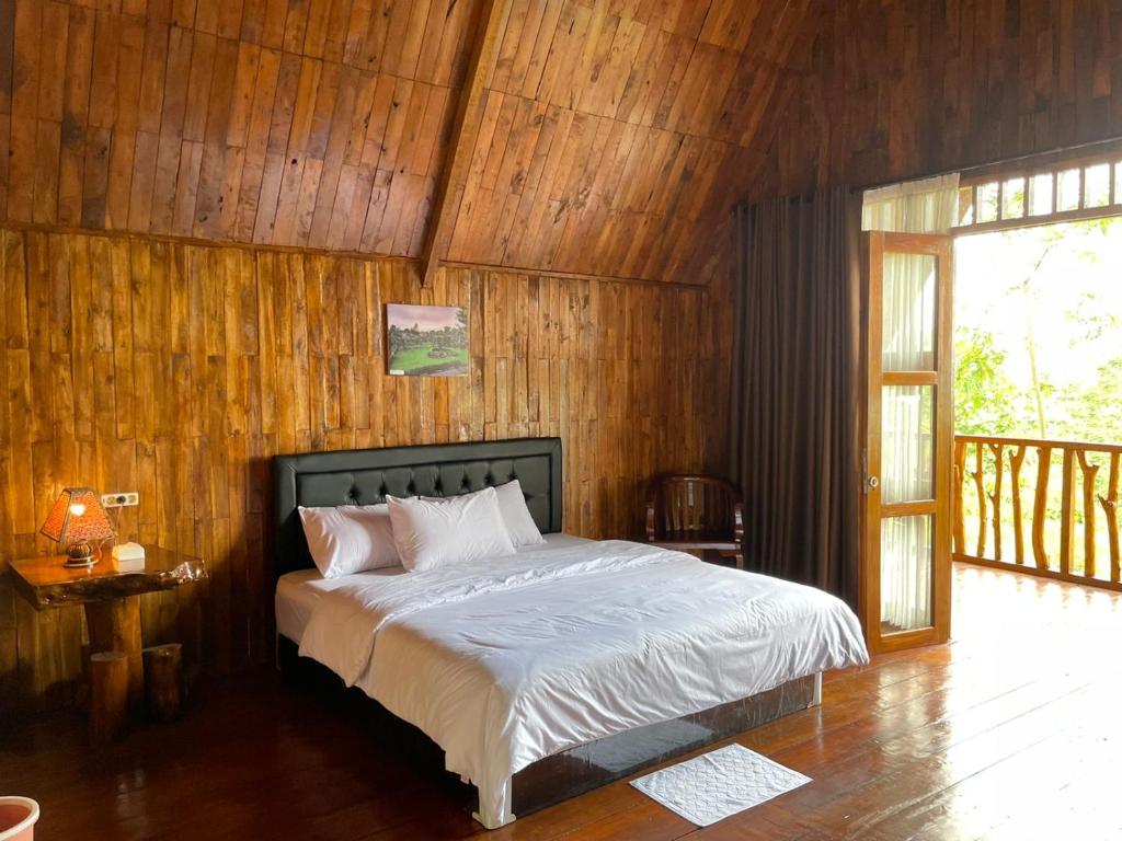 a bedroom with a bed and a wooden wall at Vila Glamping Lembah Kelud Kediri in Berni