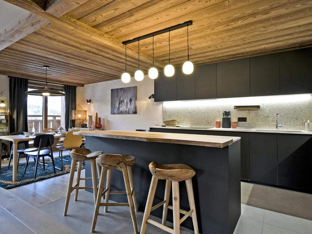 a kitchen with a counter and stools in a room at Charmant Appartement à Méribel - 3 Chambres, 6 Pers, Balcon & TV, Services Inclus - FR-1-613-33 in Méribel