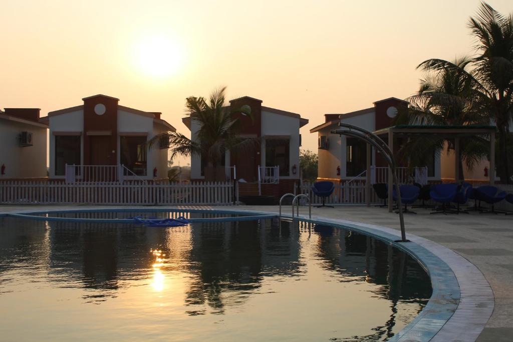 a pool at a resort with the sun setting at Flamingo Club and Resort Una 3 Km Away from Diu Check Post in Diu