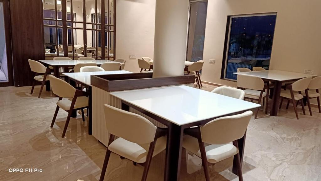 a dining room with tables and white chairs at Flamingo Club and Resort Una 3 Km Away from Diu Check Post in Diu
