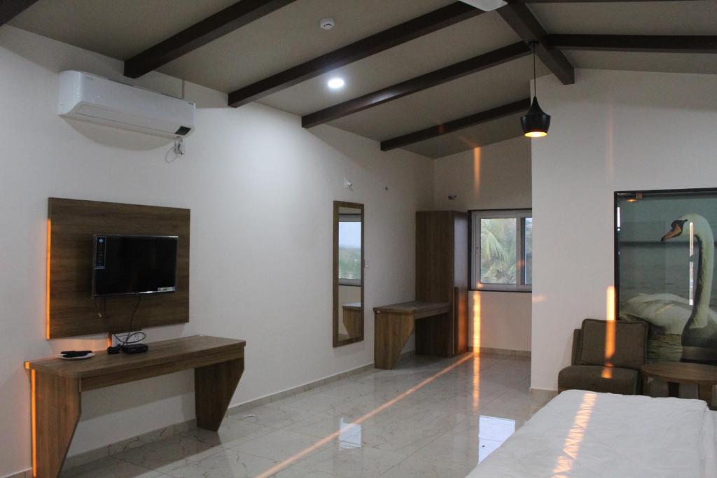 a room with a bed and a tv on a wall at Flamingo Club and Resort Una 3 Km Away from Diu Check Post in Diu