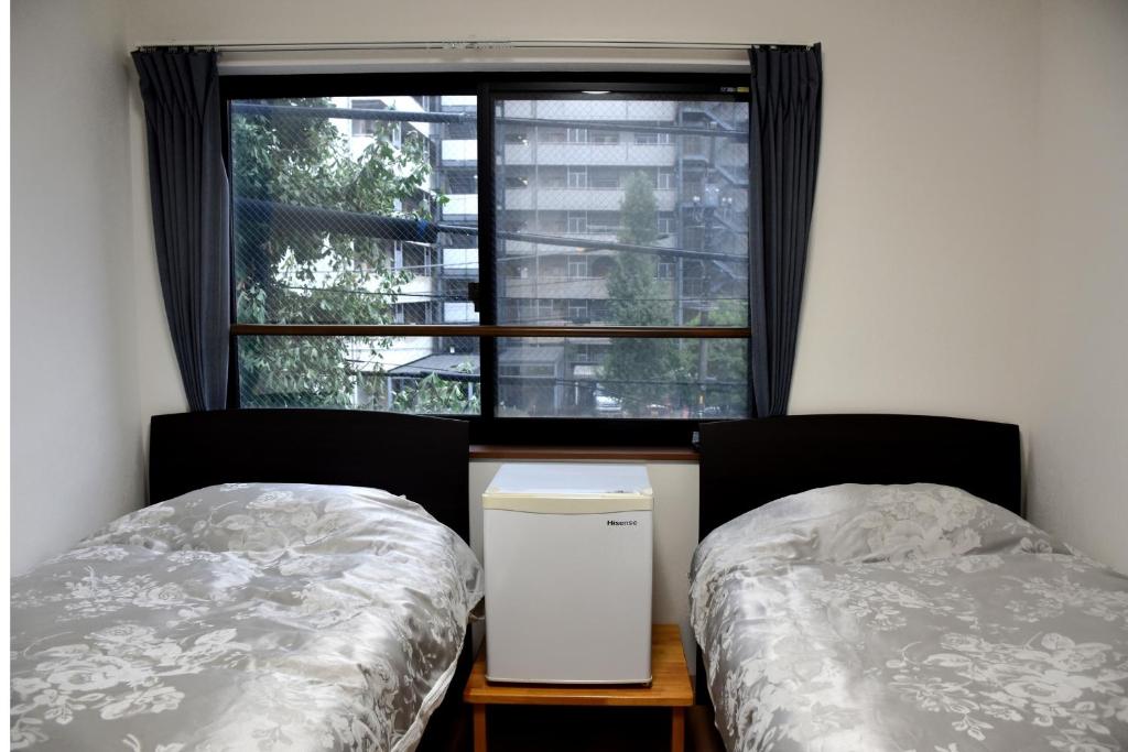 a bedroom with two twin beds and a window at B&B Nagomi in Tokyo