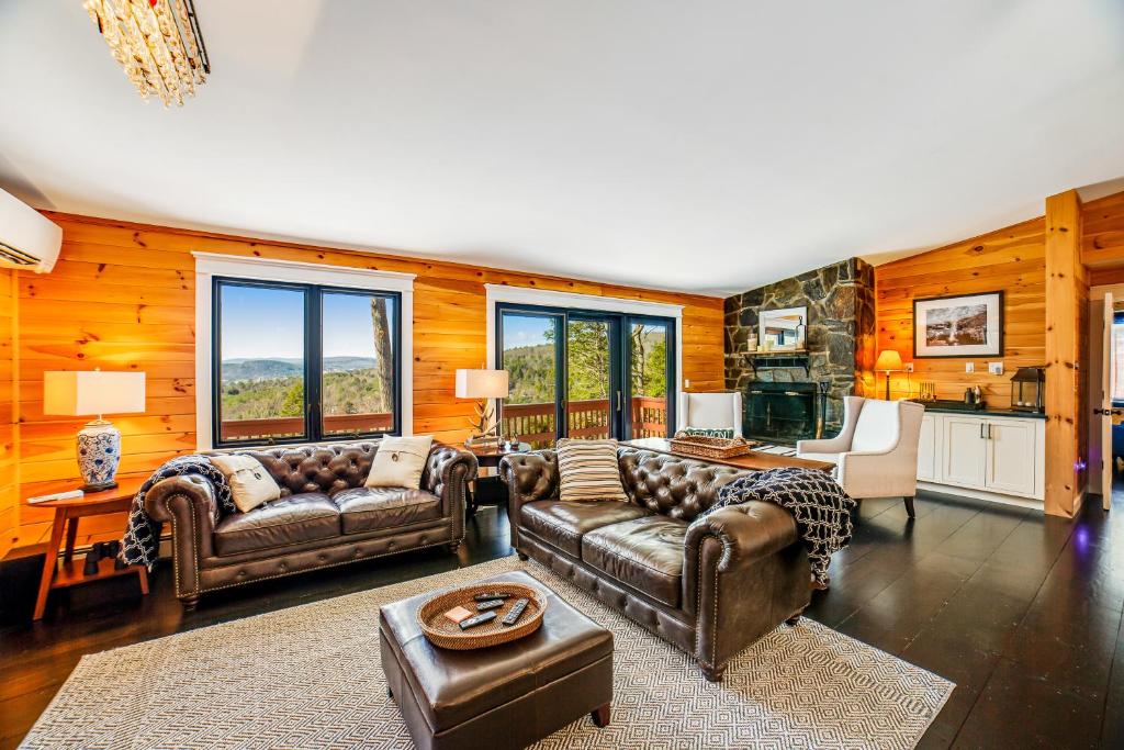 a living room with leather couches and a kitchen at Fox Lane Retreat in White River Junction
