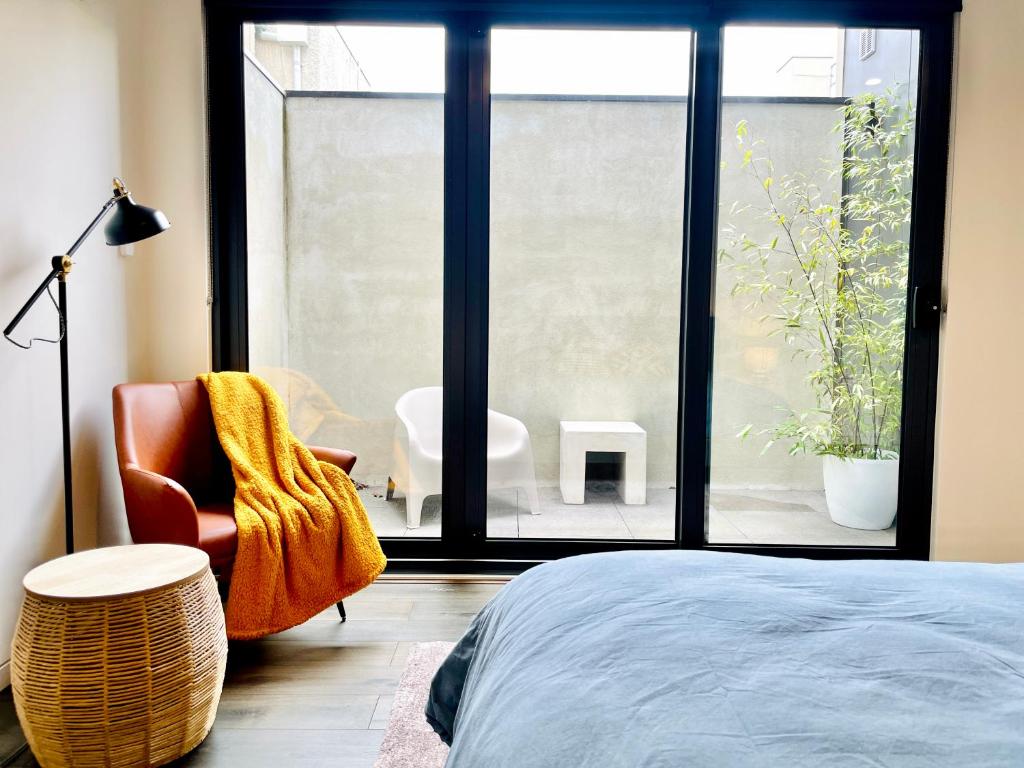 メルボルンにあるYour home on Glover St Sth Melbourne (With Parking)のベッドと椅子と窓のある寝室