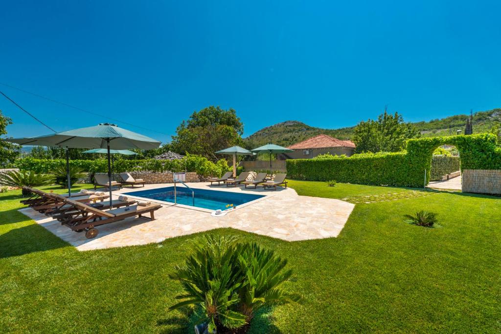 a backyard with a swimming pool and a lawn at Vila Vergatum-privacy,gym,billiards,table tennis in Donji Brgat