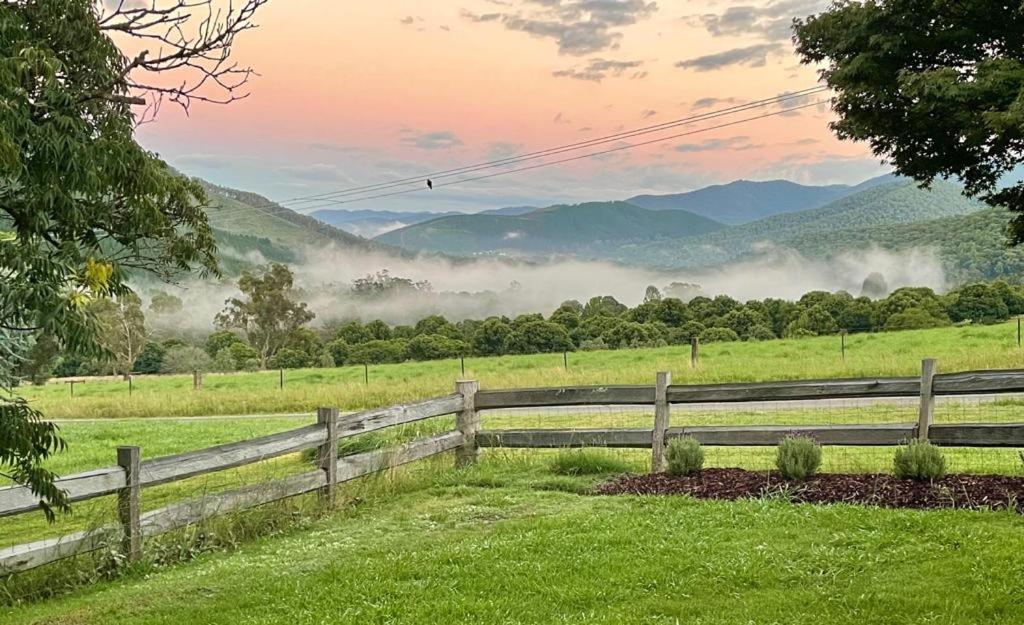 a fence in a field with a view of mountains at Wandi Bright View in Wandiligong