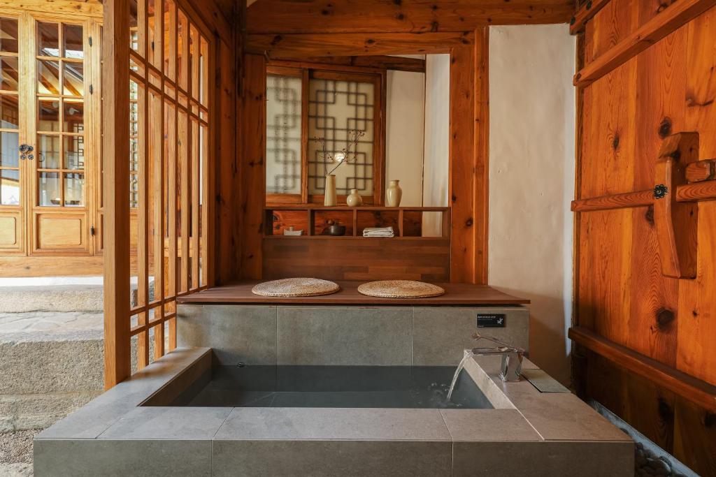 uma grande banheira num quarto com paredes de madeira em Luxury hanok with private foot bathtub - SN10 em Seul