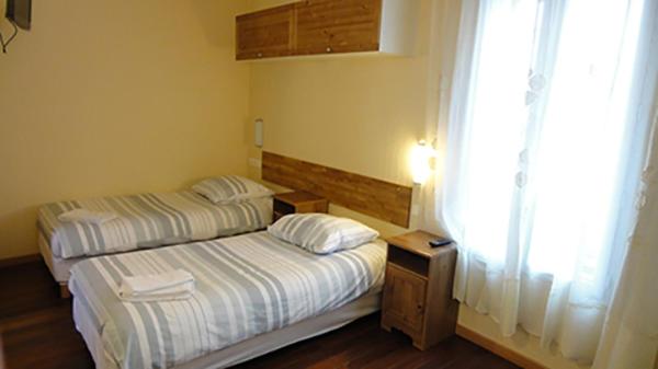 Duas camas num pequeno quarto com uma janela em Résidence Molière Hôtel Paris Montrouge em Montrouge