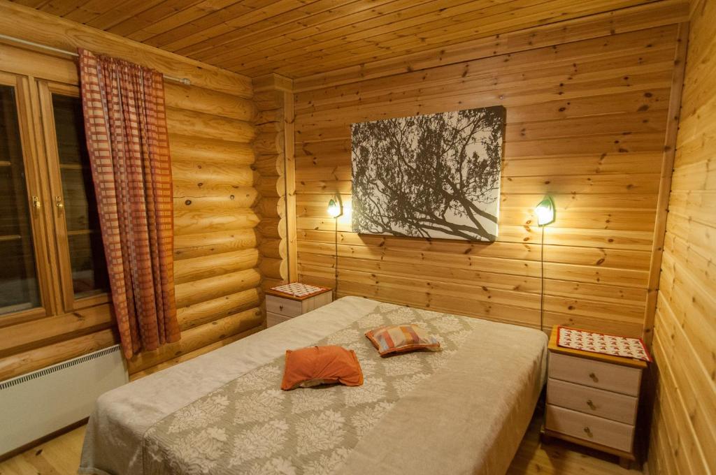 ein Schlafzimmer mit einem Bett in einer Holzhütte in der Unterkunft Välituvan lomamökit in Punkaharju