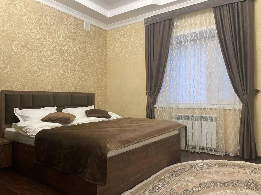 Un dormitorio con una cama grande y una ventana en Grand SPA Hotel, en Kostanái