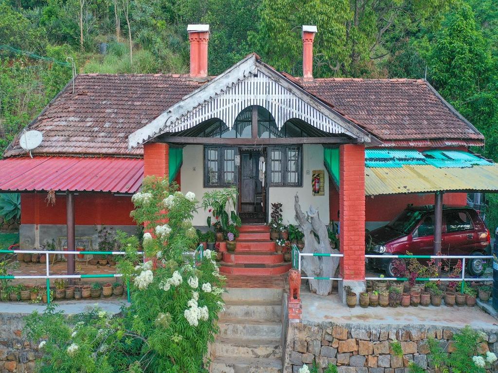 une petite maison avec un toit rouge et vert dans l'établissement DEVASHOLA HOMESTAY, à Coonoor