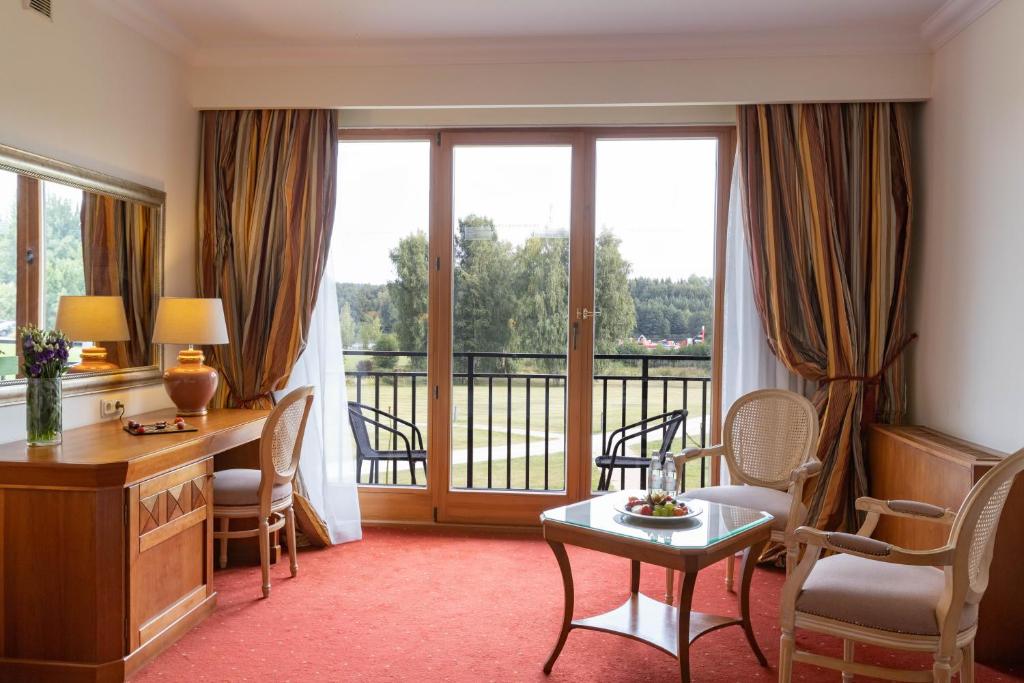 a hotel room with a desk and a balcony at Vilnius Grand Resort in Ežeraičiai