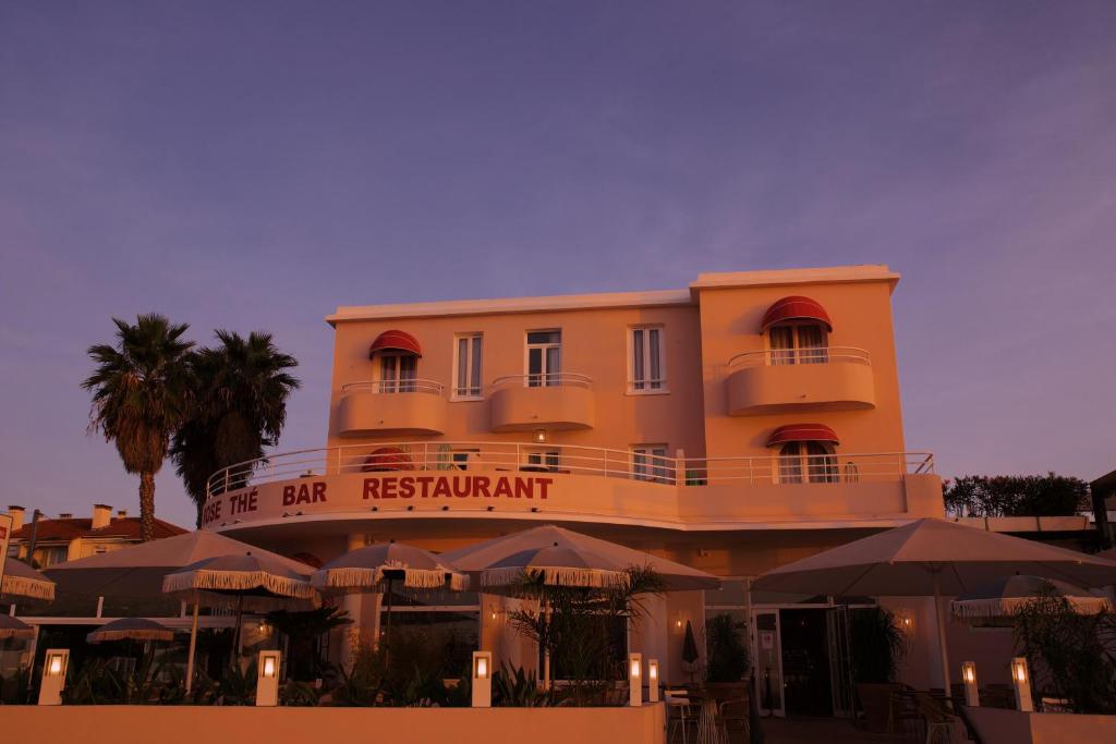 a building with a restaurant with umbrellas in front of it at Le Rose Thé in La Ciotat