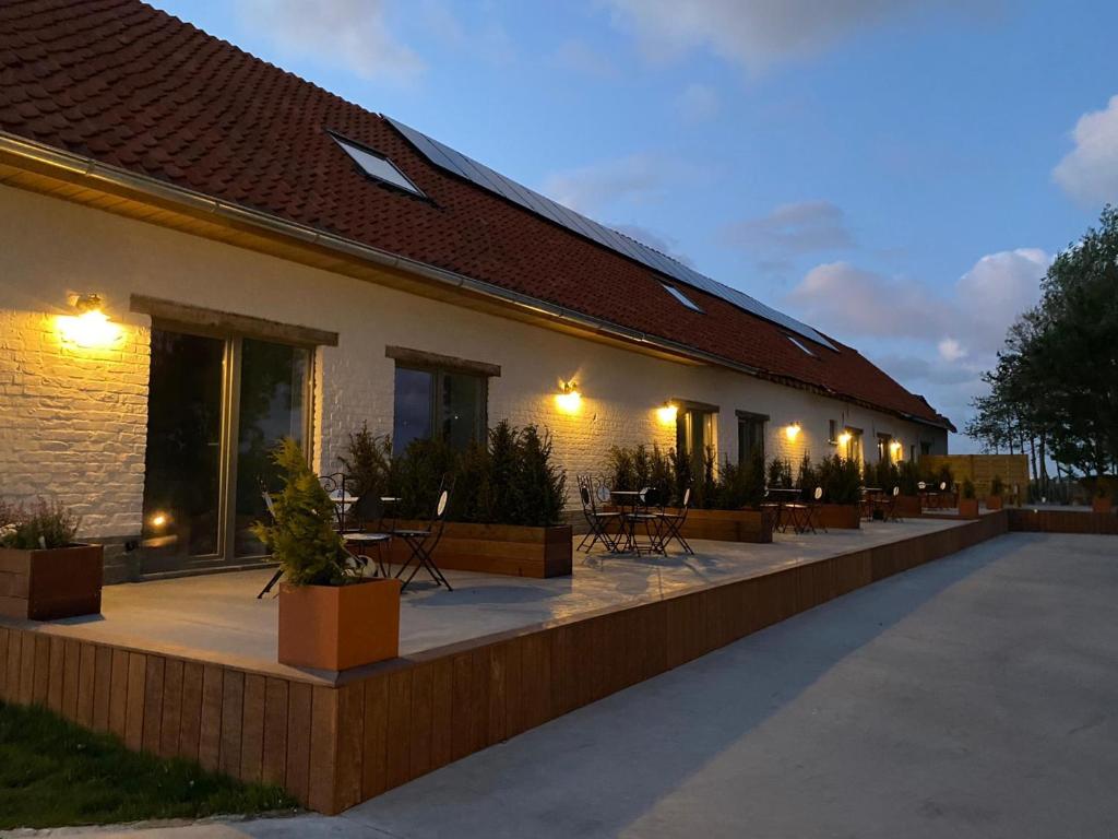 a building with a patio with tables and chairs at Handbooghoeve Leffinge in Leffinge