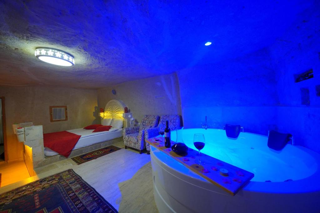 a bathroom with a tub and a bedroom with a bed at Fosil Cave Hotel in Ortahisar