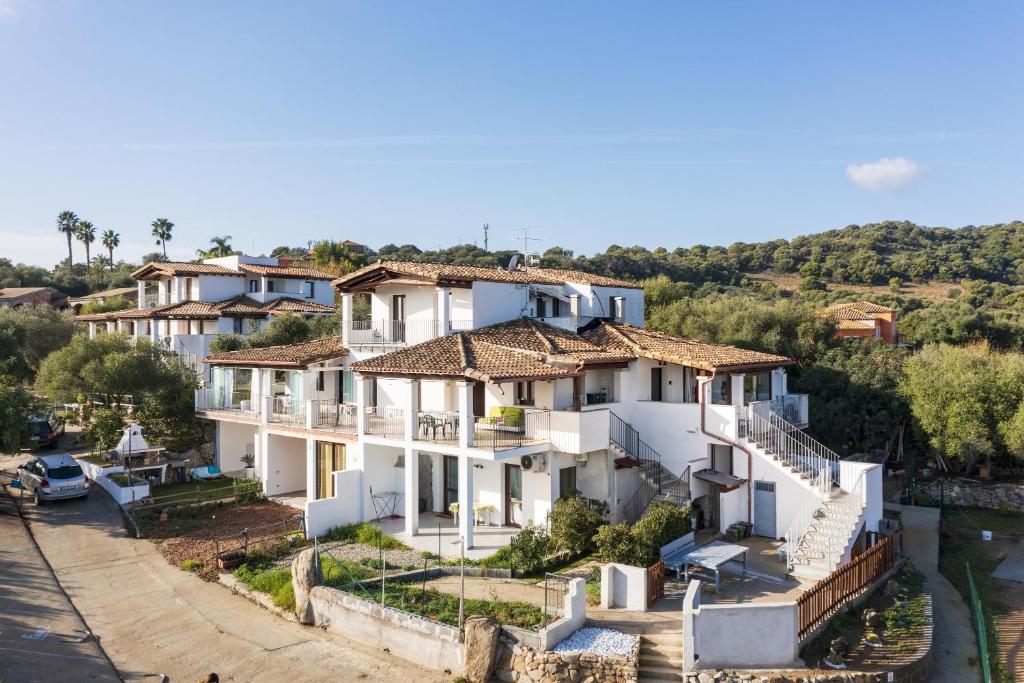 a large white house on a hill next to a river at Giorgio Home Holiday in Bari Sardo