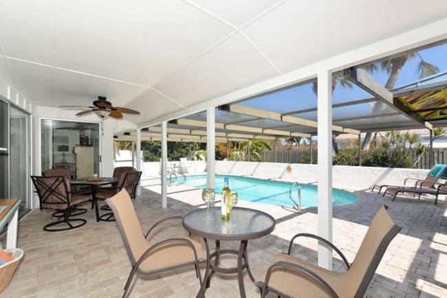 un patio con mesa, sillas y piscina en Pleasant Palms Home, en Holmes Beach